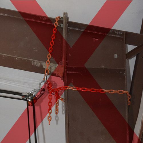 A photo of some unsafe aerial rigging, including misuse of chain, and a triloaded carabiner.